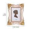 A rectangular, ornate pink and gold decorative photo frame with a textured white mat and a silhouette of a head.