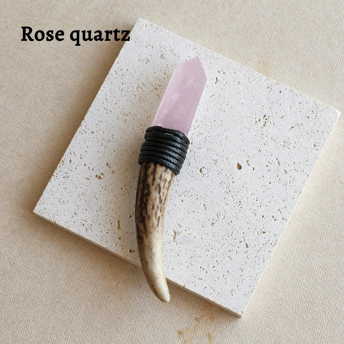 A rose quartz crystal point mounted on a dark wood wand with black cord for spiritual decor.