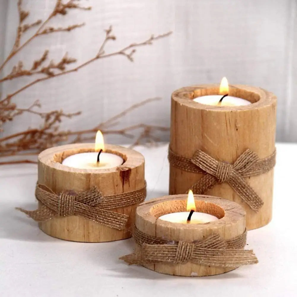 A set of rustic wooden stump candle holders tied with twine, displayed on a white surface next to dry branches.