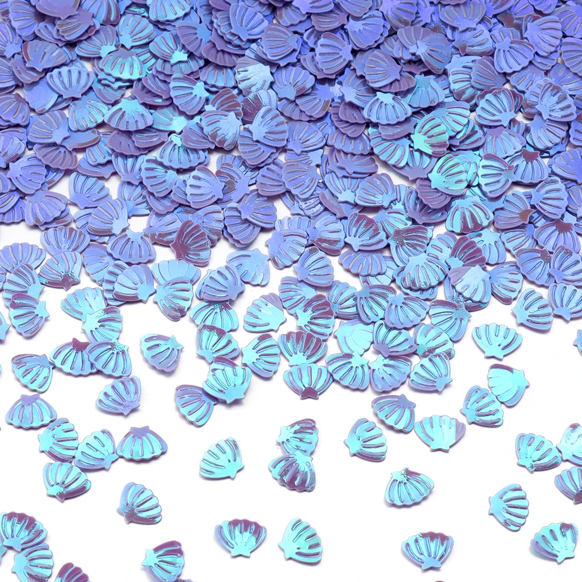 A pile of iridescent blue and purple sea shell PVC sequins for nail art and craft decoration.