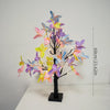 A decorative light featuring a black tree branch adorned with colorful butterfly-shaped LED lights in shades of purple, pink,