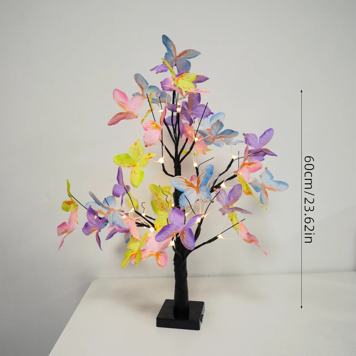 A decorative light featuring a black tree branch adorned with colorful butterfly-shaped LED lights in shades of purple, pink,