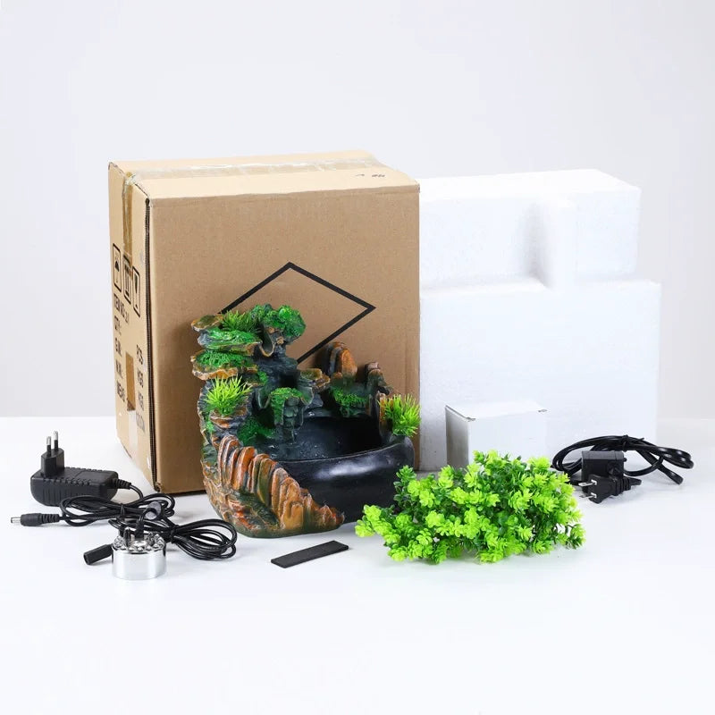 A brown cardboard box containing a resin waterfall desktop fountain with LED lighting and associated accessories.