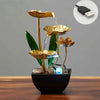 A golden lotus pond tabletop water fountain with green leaves and blue LED lighting in a black pot.