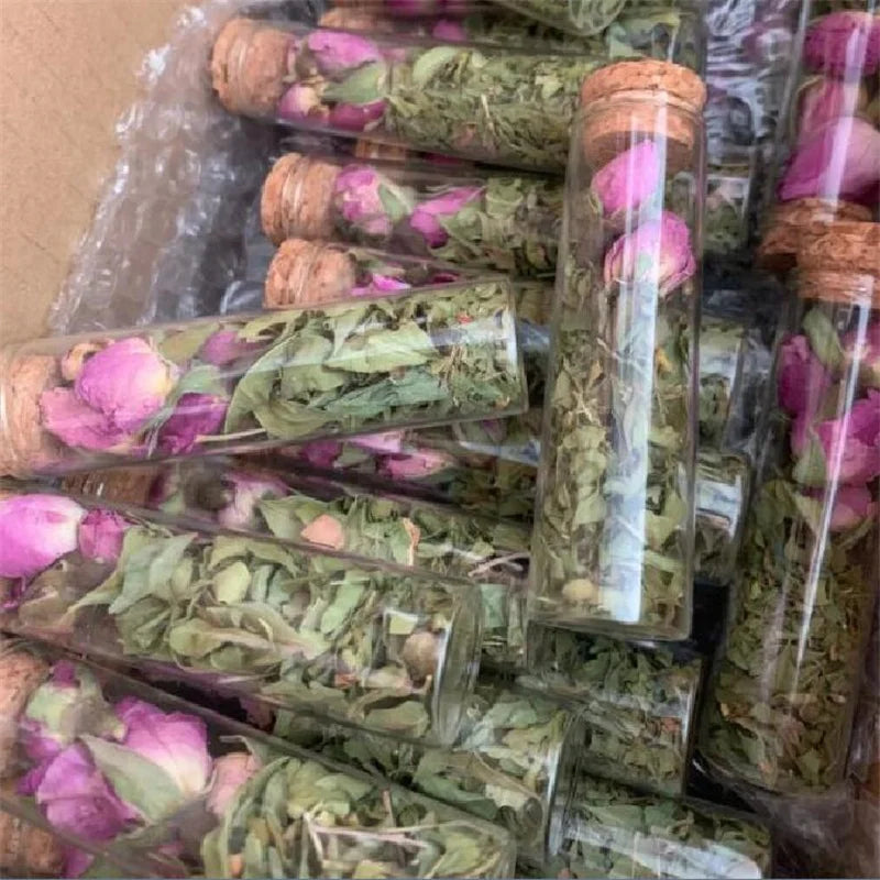 Mini glass bottles with cork stoppers filled with dried pink and green floral herbs