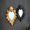 A pair of ornate wall pendants shaped like hearts, one gold and one black, featuring a flame design.