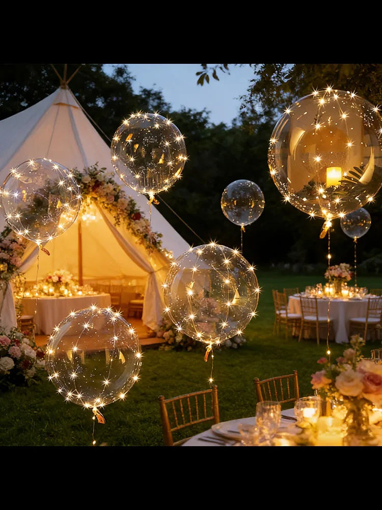 Golden LED illuminated party balloons floating above a rustic outdoor wedding reception.