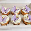 A box containing six cupcakes topped with purple butterfly decorations.