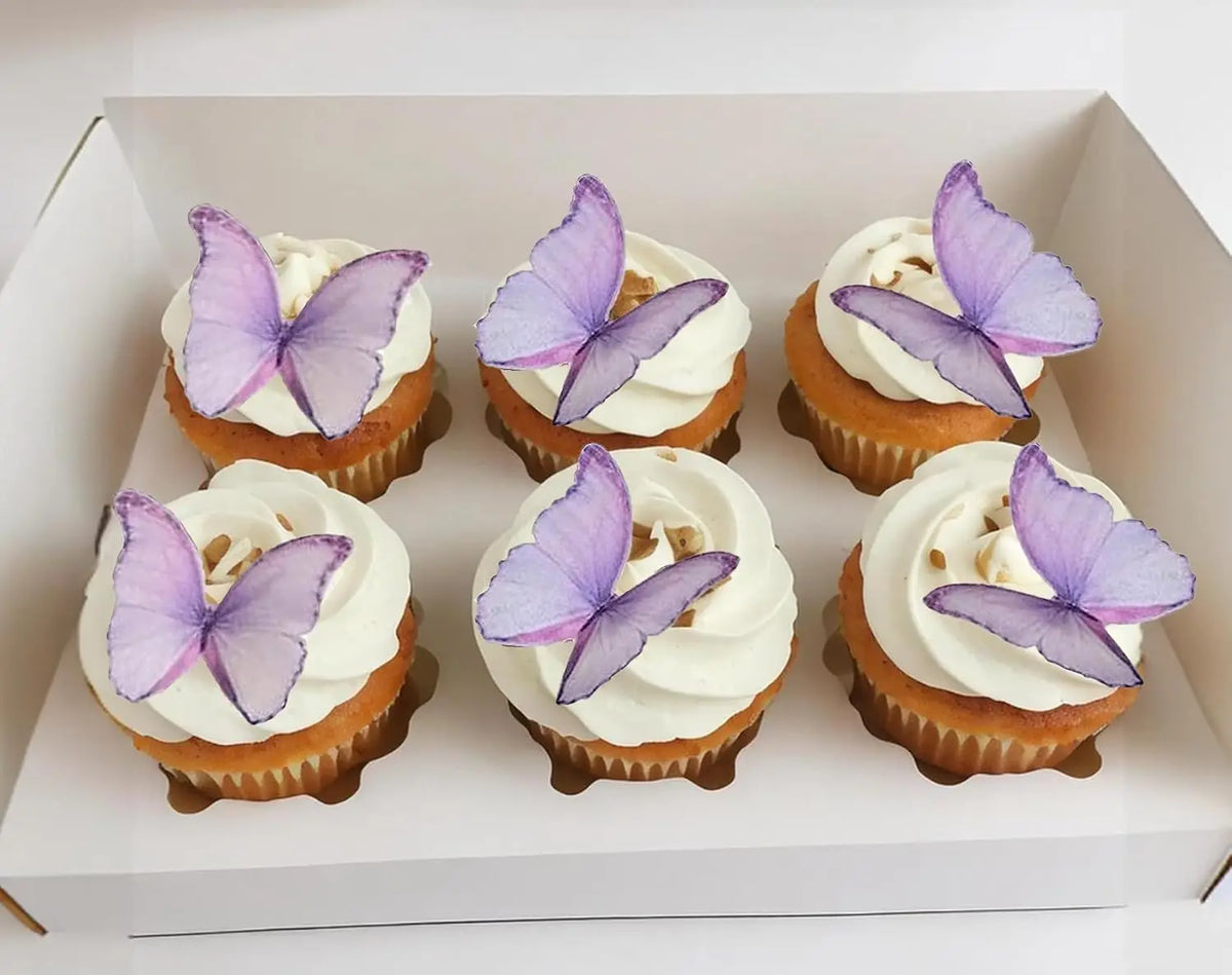 A box containing six cupcakes topped with purple butterfly decorations.