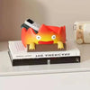 A resin cartoon fire person tray with an orange head and yellow horns rests on a stack of books.