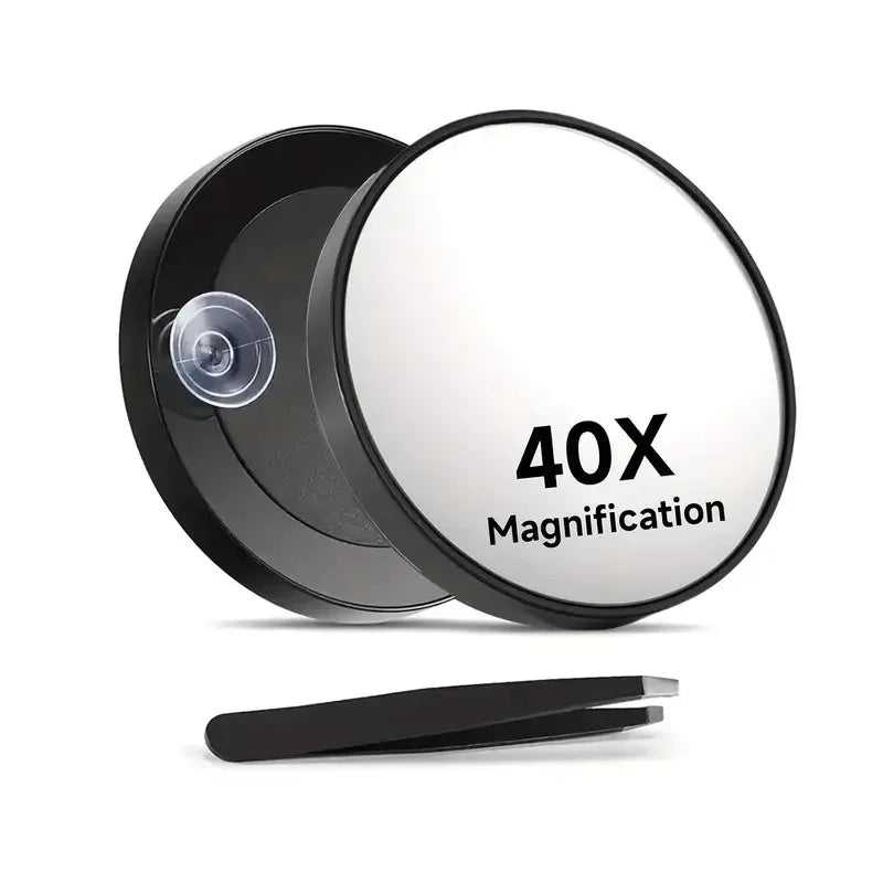 A black magnifying compact mirror with a circular lens and a suction cup is shown on a white background.