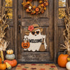 A wooden ghost door hanging featuring a witch hat design, surrounded by autumn foliage and pumpkins.