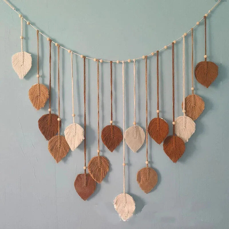 Bohemian macrame leaf wall hanging featuring various dried leaves and tassels suspended by twine.