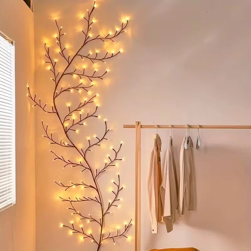 A decorative branch of LED willow vine lights mounted on a wall next to a wooden clothing rack.
