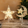 A sparkling LED Christmas tree star and crescent moon topper displayed on a wooden surface.
