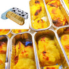 Disposable aluminum foil baking trays with lids filled with baked yellow food