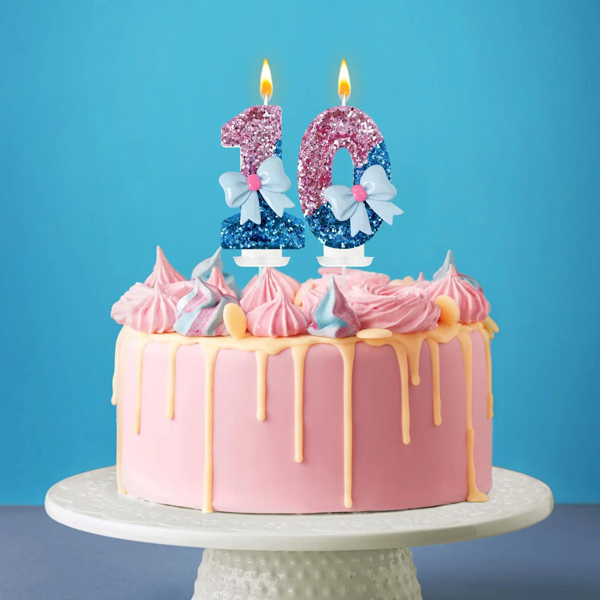 A pink birthday cake decorated with glitter candles shaped like the number 1 and 0, topped with pink frosting swirls.