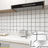 A modern kitchen featuring a stainless steel range hood above a white tiled backsplash and countertop.