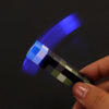 A hand holds a pixel art mini flashlight keychain with a blue LED light shining brightly.