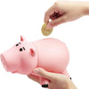 A hand is depositing a gold coin into an adorable pink piggy bank for children.