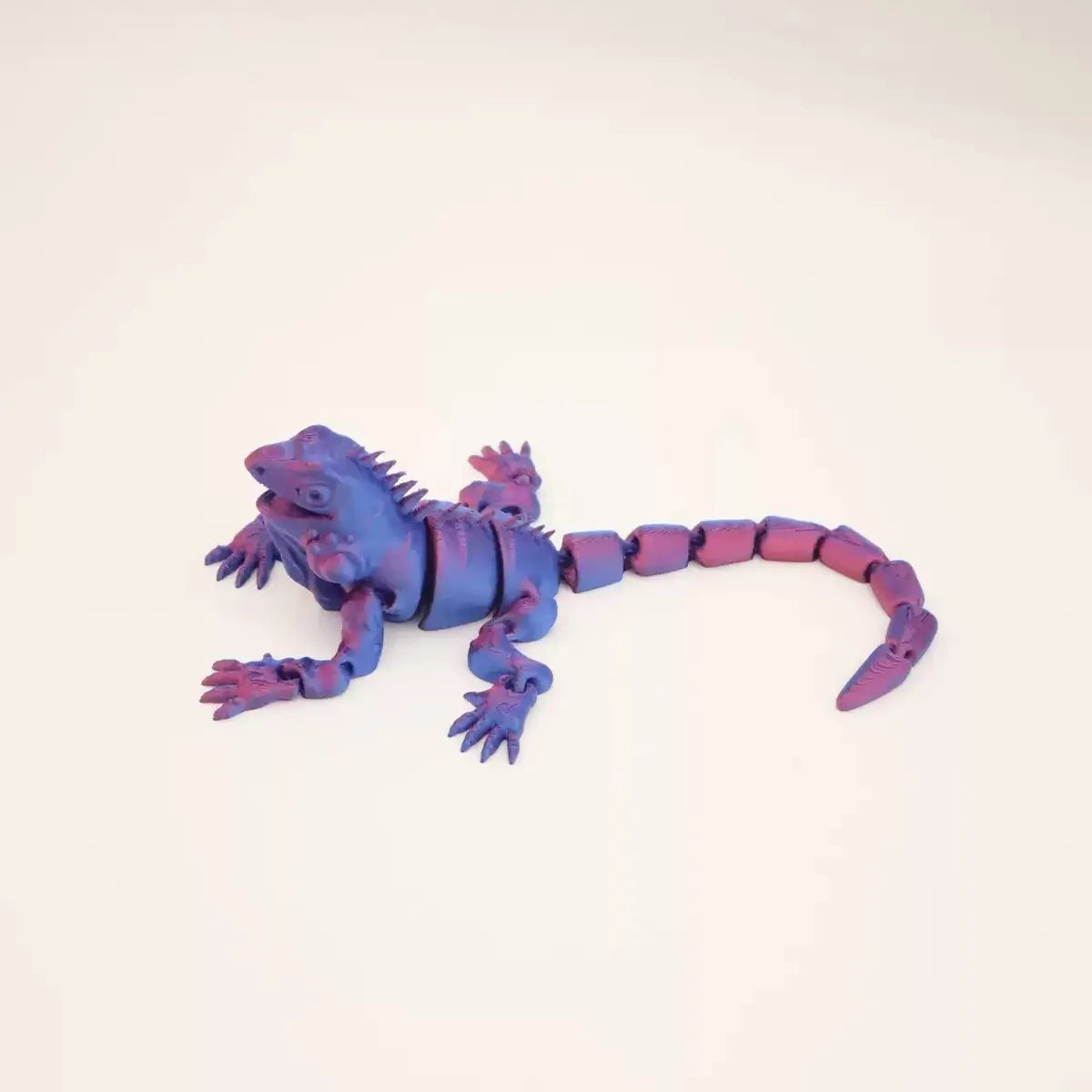 A purple articulated 3D printed lizard figurine lying on a white surface.