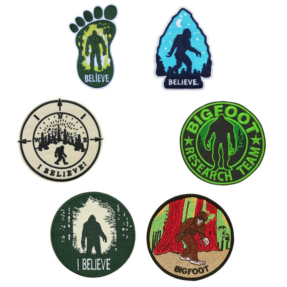 A collection of embroidered patches featuring Bigfoot imagery, including a green foot print, a blue silhouette, and circular 