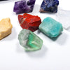 A collection of natural crystal healing stones in various colors including purple, red, green, and clear quartz on a white su