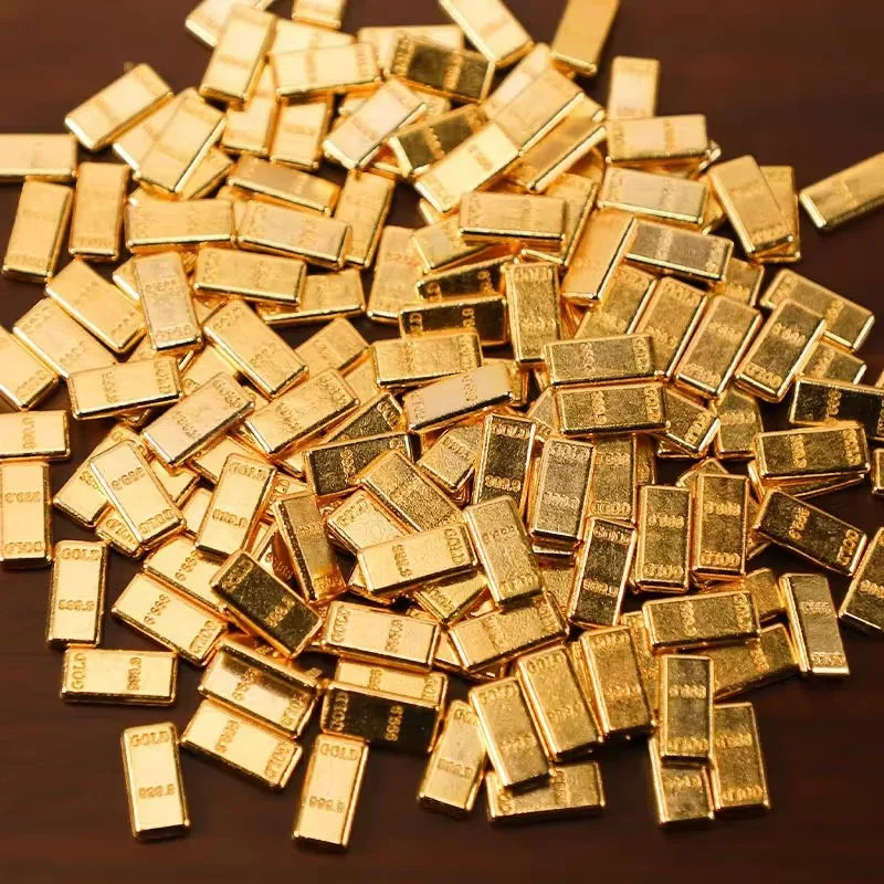 A pile of small, rectangular simulated gold bars scattered on a dark surface.