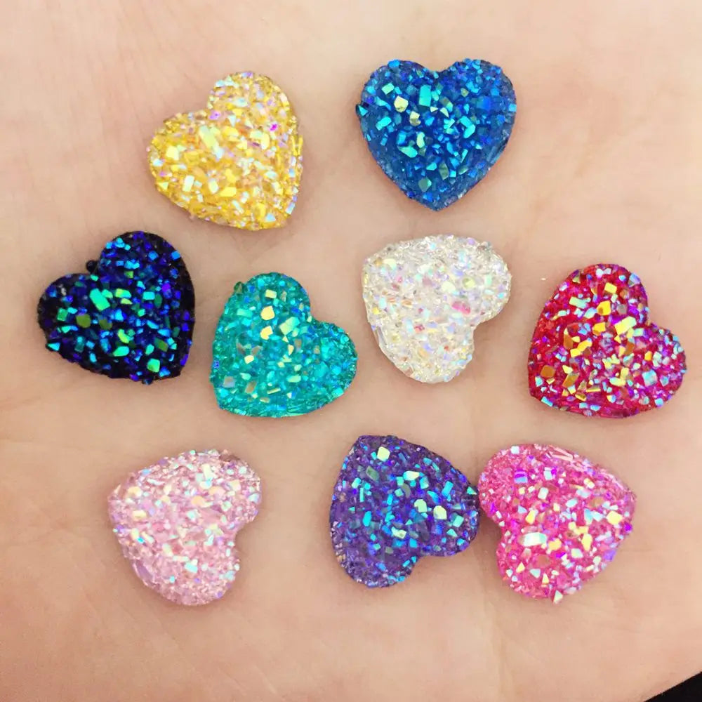 Eine Sammlung von neun herzförmigen Strass-Ornamenten in verschiedenen Farben, darunter Gold, Blau, Lila, Pink und Iris