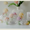 A bouquet of artisan tulips in various shades of pink and yellow displayed with sheer white wrapping on a white surface.