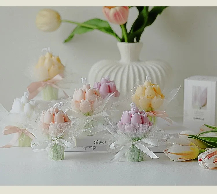 A bouquet of artisan tulips in various shades of pink and yellow displayed with sheer white wrapping on a white surface.