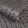 Roll of self-adhesive 3D wood grain wall panels in dark gray showing the textured surface and core.