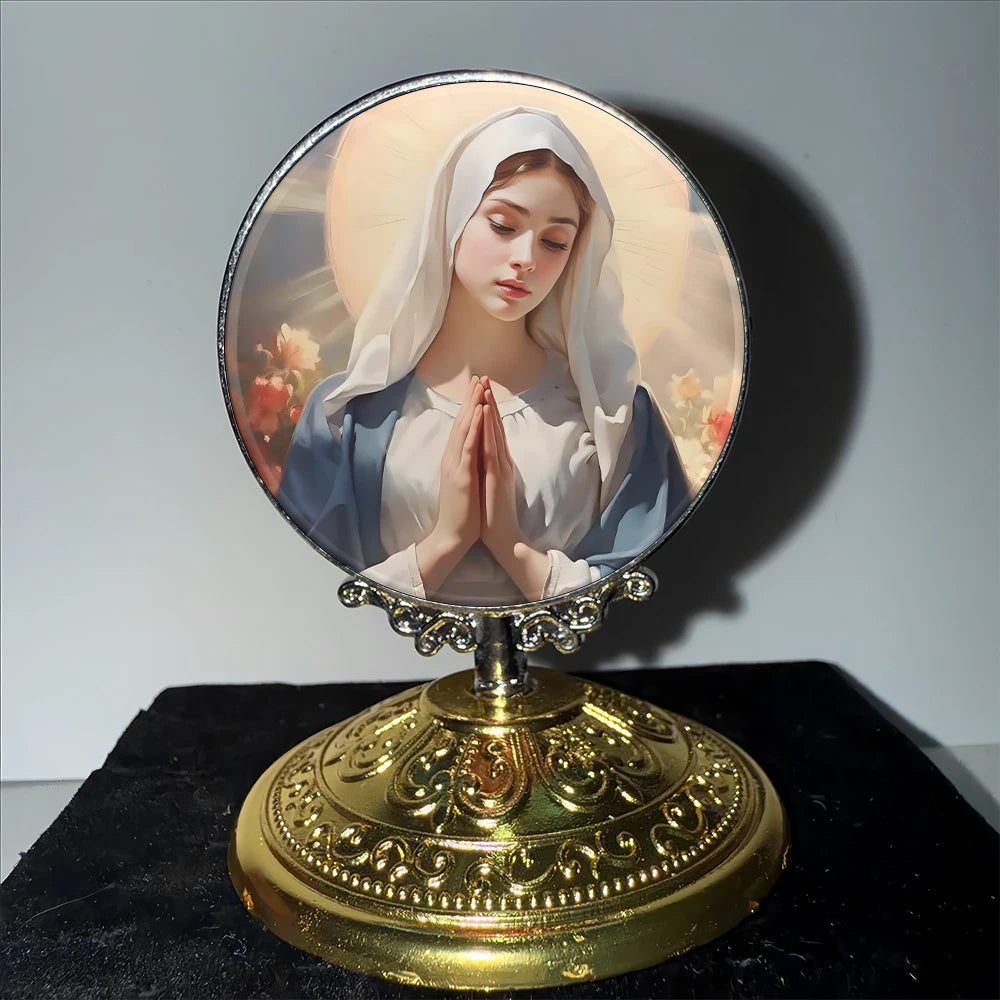 A round religious ornament featuring a depiction of the Virgin Mary with folded hands set on a golden base.