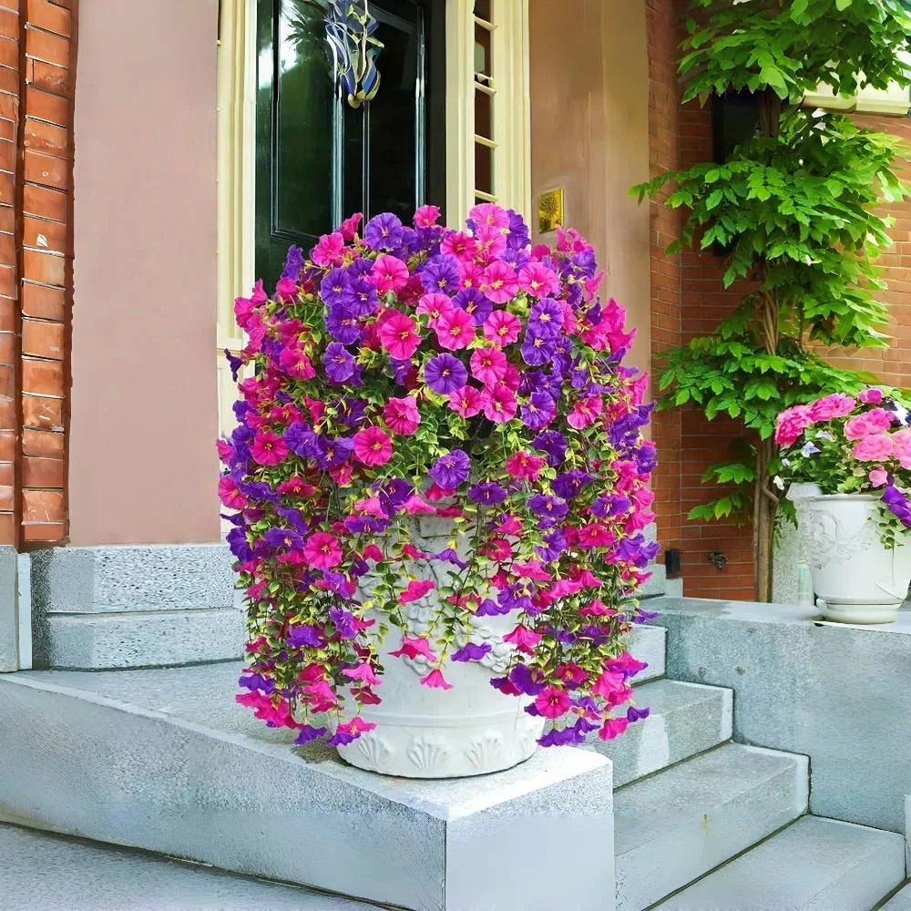 A vibrant display of artificial morning glory hanging vines in shades of purple and pink on a white pedestal.