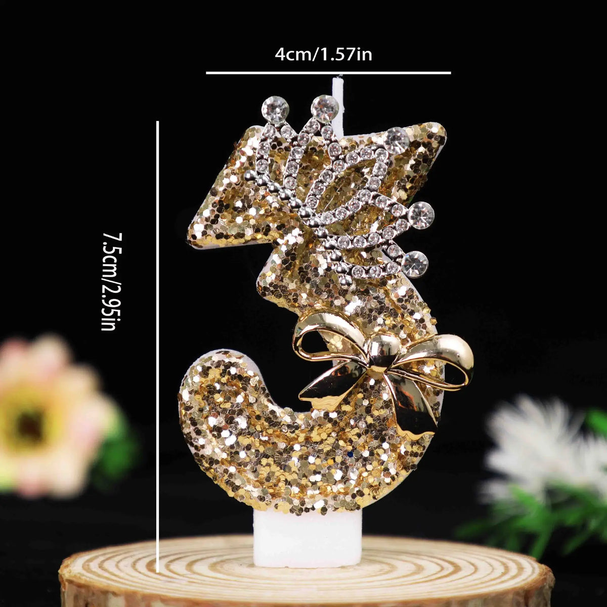 Gold glitter number cake topper featuring a bow made of rhinestones on a white candle base.
