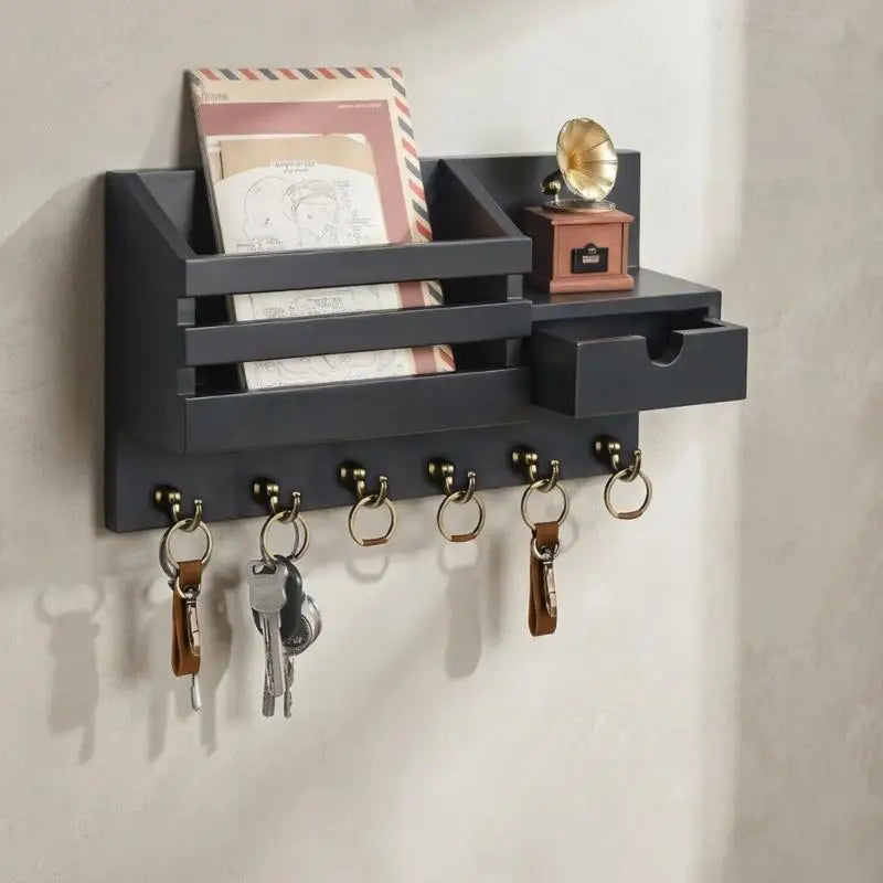 A dark gray wall-mounted organizer for mail and keys featuring a storage tray and a small drawer.
