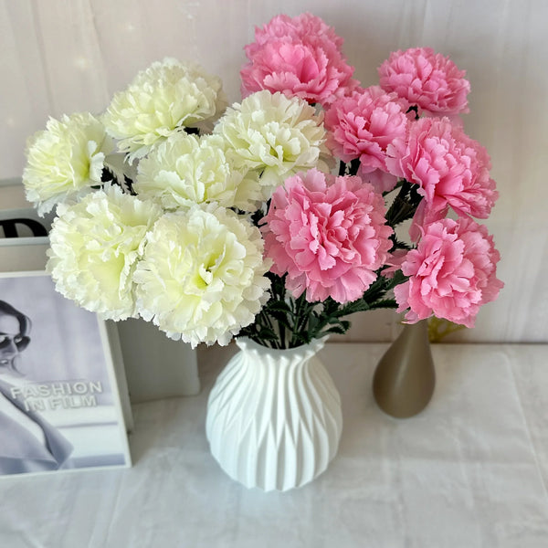 A bouquet of pink and cream silk artificial chrysanthemum flowers in a white vase.