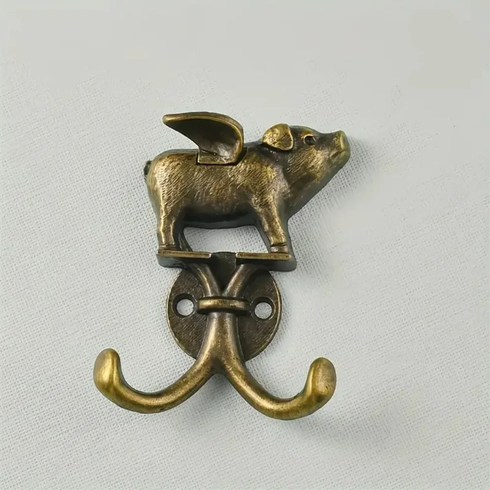 A brass decorative metal wall hook shaped like a rodent, used for hanging items.