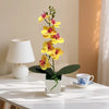 A small potted artificial plant with yellow and pink flowers displayed on a white table.