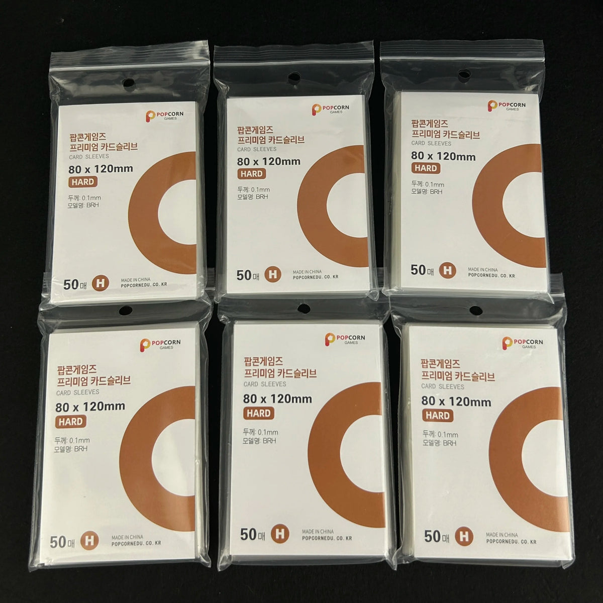 A pack of 50 Crystal Clear Protective Card Sleeves in brown cardboard sleeves with a white label and gold foil text.