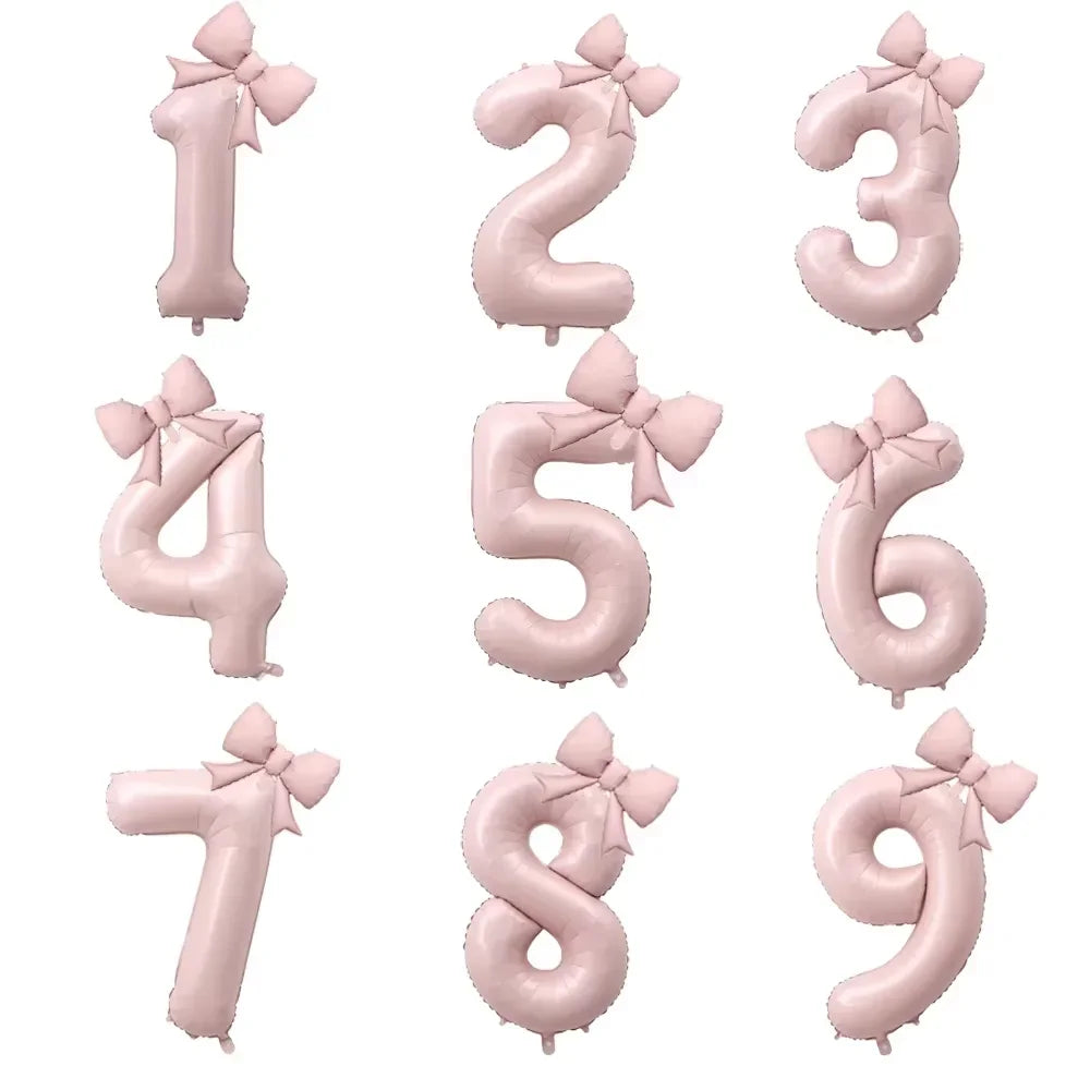 A set of large pink foil number balloons from 0 to 9, each decorated with a bow.