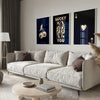 A modern living room features a light sofa and wooden coffee table with a set of dark framed art prints.