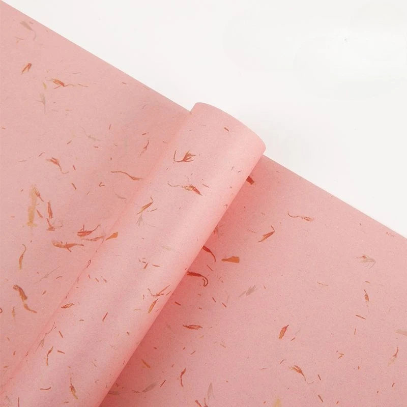 Pink decorative packaging paper with scattered gold flower petals rolled up.