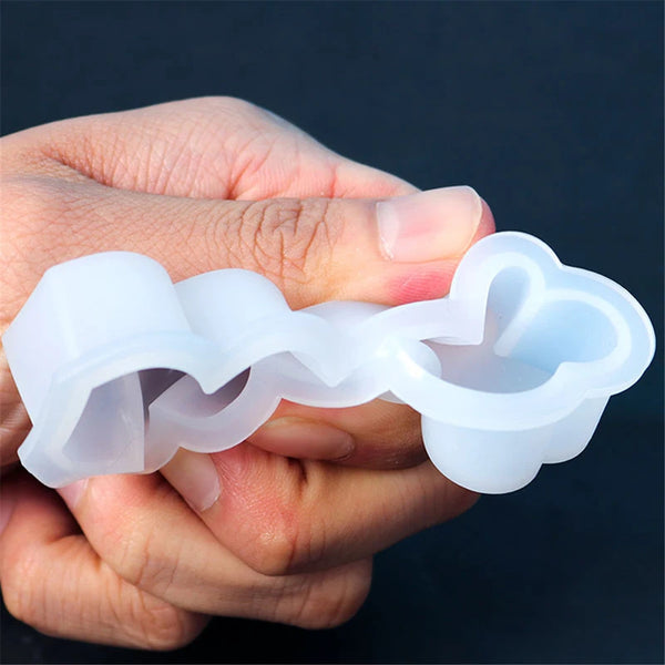 A hand holds a clear silicone mold kit with two heart-shaped cavities for candle making.