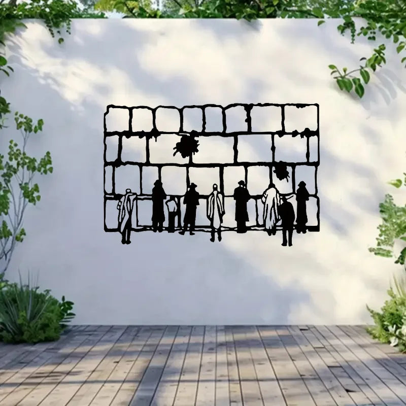 Schwarze Silhouette eines dekorativen Metallzauns mit menschlichen Figuren darauf, an einer weißen Wand montiert.