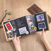 A hand holds an open DIY memory scrapbook album displaying photos and handwritten notes.