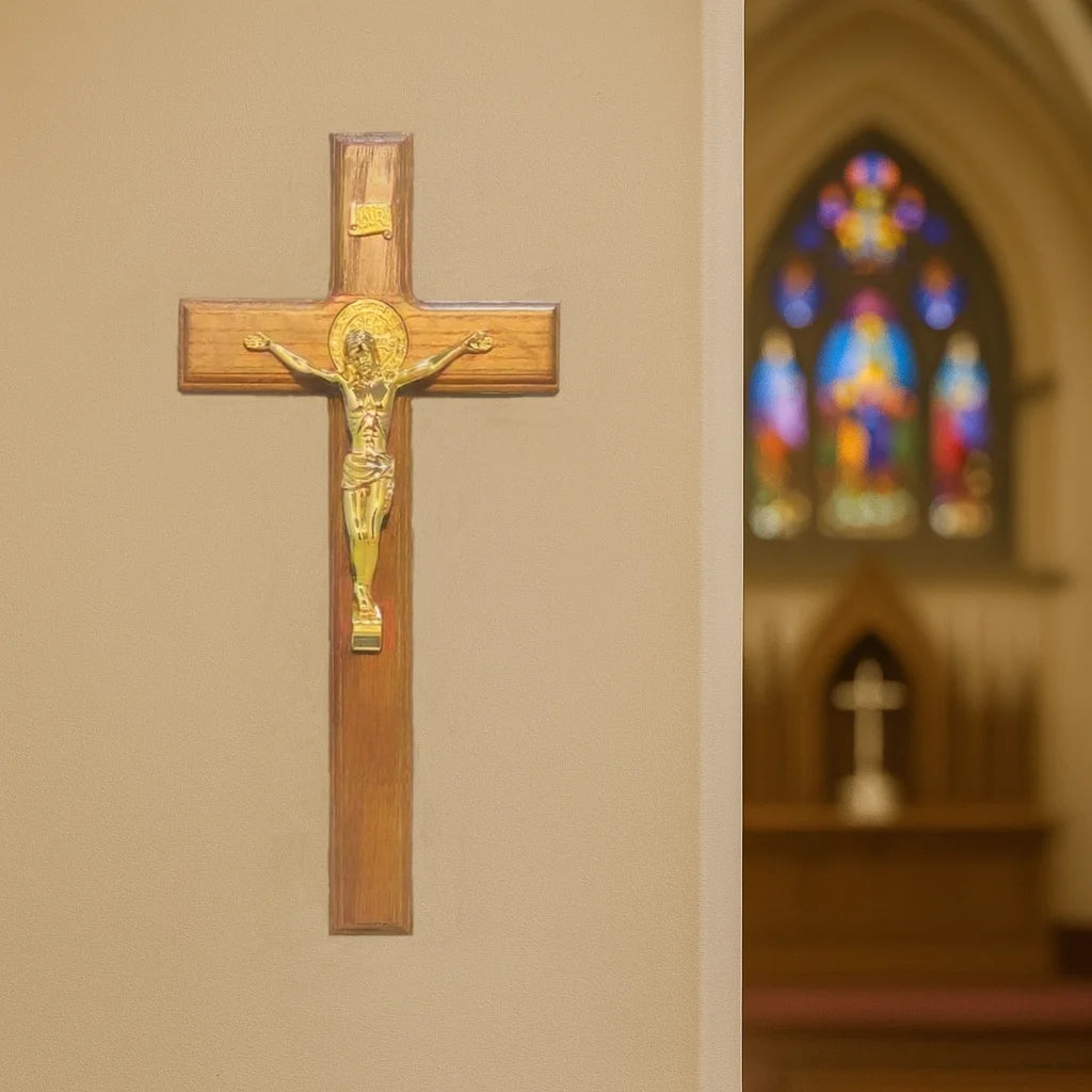A wooden crucifix with a gold Jesus figure mounted on a light beige wall.