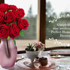 A bouquet of deep red artificial silk roses in a pink vase set on a decorated table.