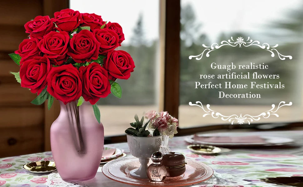 A bouquet of deep red artificial silk roses in a pink vase set on a decorated table.