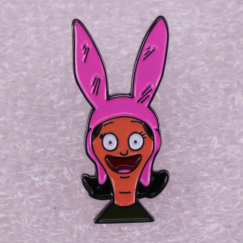 A pink enamel pin badge featuring a cartoon character with large eyes and a wide smile.